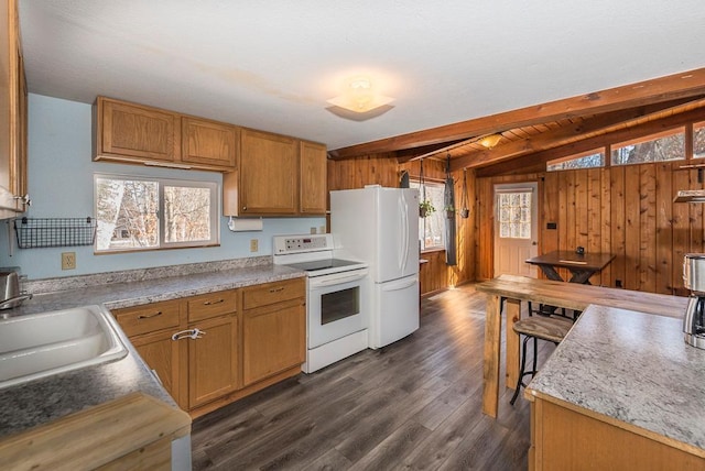 kitchen with vaulted ceiling with beams, wooden walls, white appliances, dark wood-type flooring, and a sink