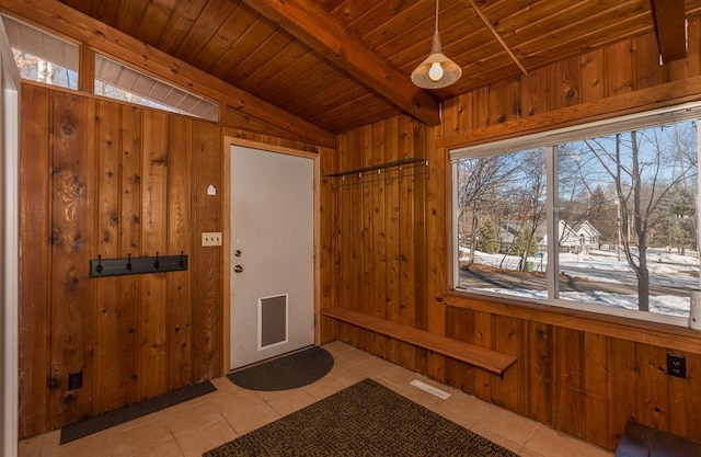 tiled entryway featuring wood walls, wood ceiling, and a healthy amount of sunlight