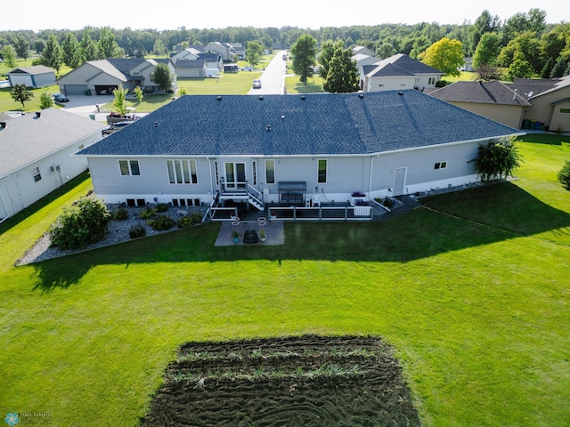 rear view of house with roof with shingles, a lawn, and a residential view