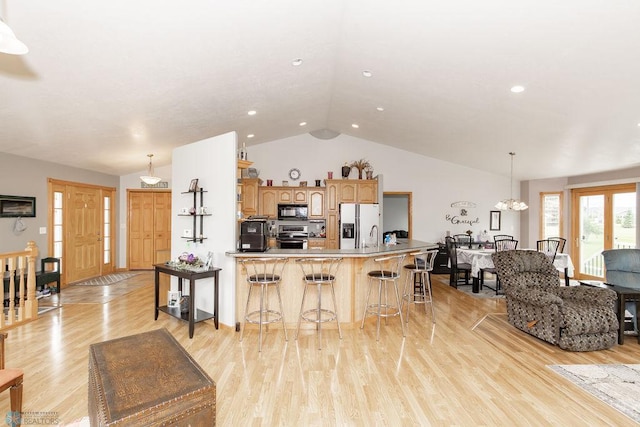 kitchen with a large island, lofted ceiling, light wood-style flooring, refrigerator with ice dispenser, and black microwave