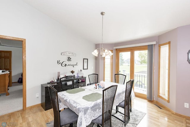 dining space with light wood-type flooring, vaulted ceiling, a notable chandelier, and baseboards