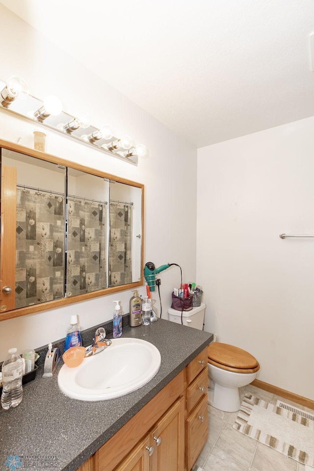 bathroom with curtained shower, tile patterned flooring, toilet, vanity, and baseboards