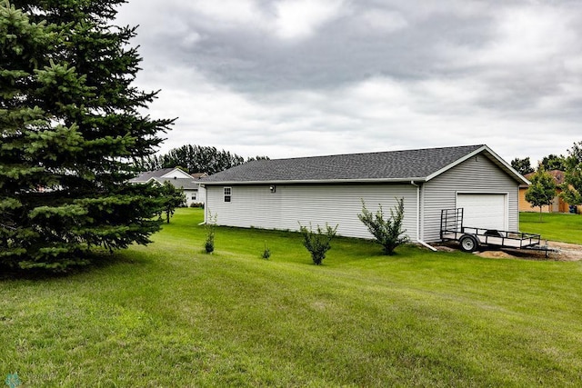 view of side of home featuring a garage, a lawn, and roof with shingles