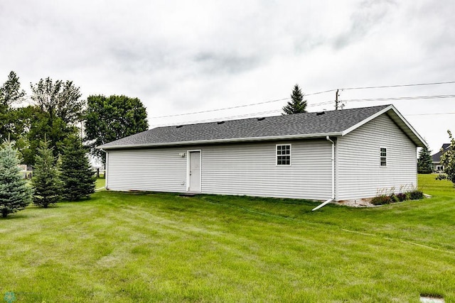 rear view of house with a shingled roof and a lawn