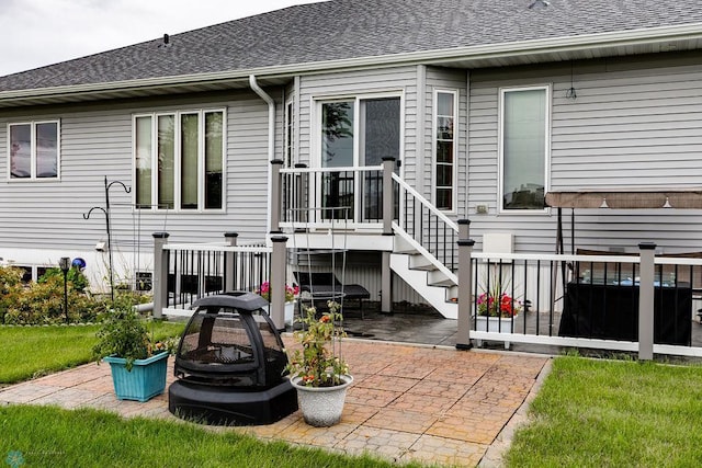 back of property with roof with shingles and a patio