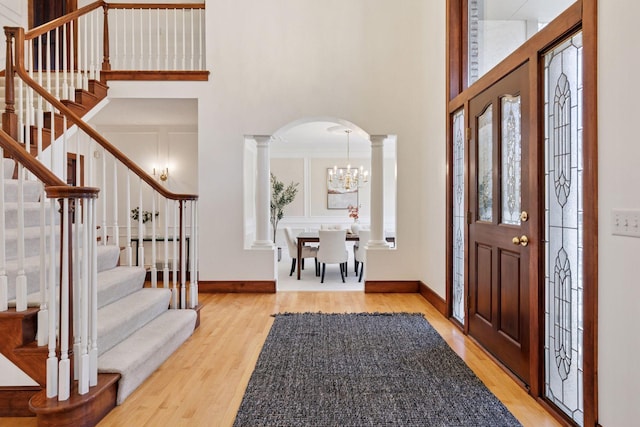 foyer with arched walkways, stairway, wood finished floors, a high ceiling, and a notable chandelier