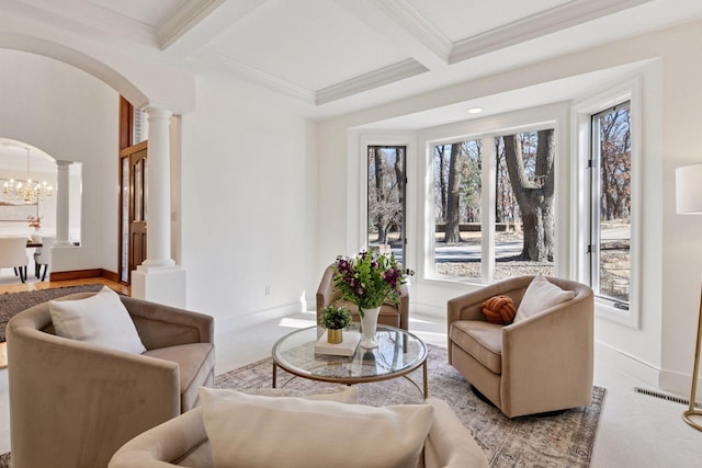 living area featuring arched walkways, beamed ceiling, ornate columns, and an inviting chandelier