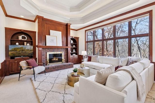 living area featuring built in features, a tray ceiling, a fireplace, ornamental molding, and light carpet