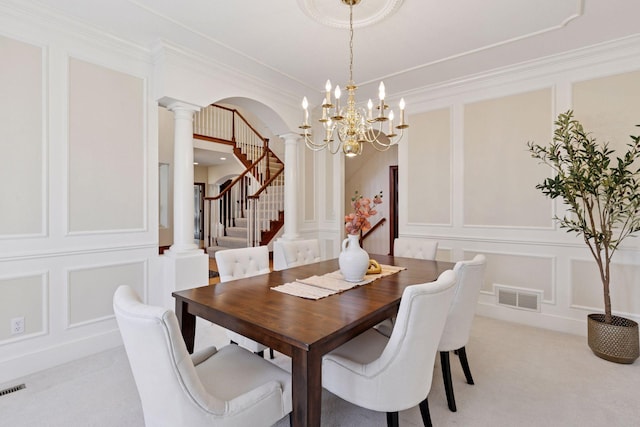 dining space with light colored carpet, visible vents, a decorative wall, ornate columns, and stairs