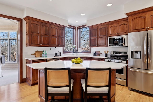 kitchen with appliances with stainless steel finishes, light countertops, a kitchen island, and a breakfast bar area