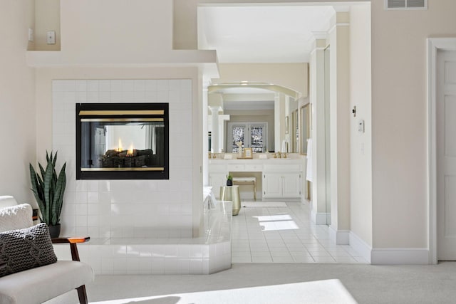 bathroom with baseboards, a fireplace, visible vents, and tile patterned floors