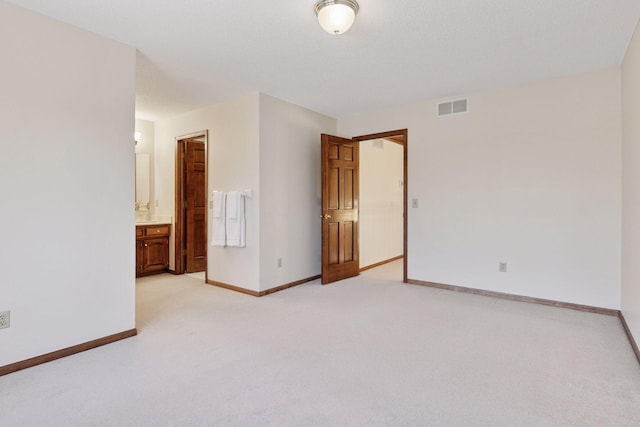 unfurnished bedroom with ensuite bath, baseboards, visible vents, and light colored carpet