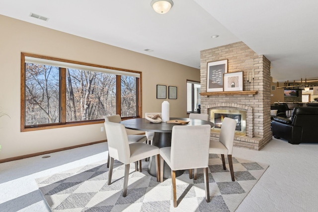 dining space with carpet, a fireplace, visible vents, and baseboards