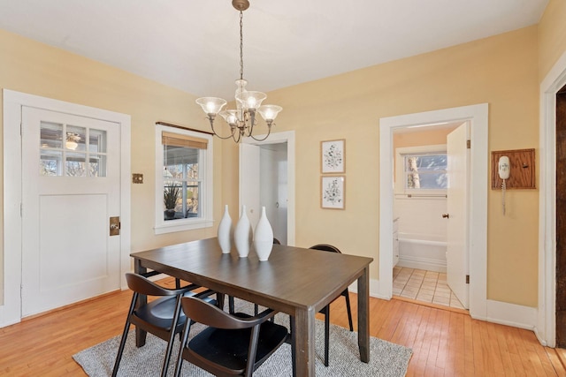 dining room featuring light wood-style floors, plenty of natural light, a notable chandelier, and baseboards