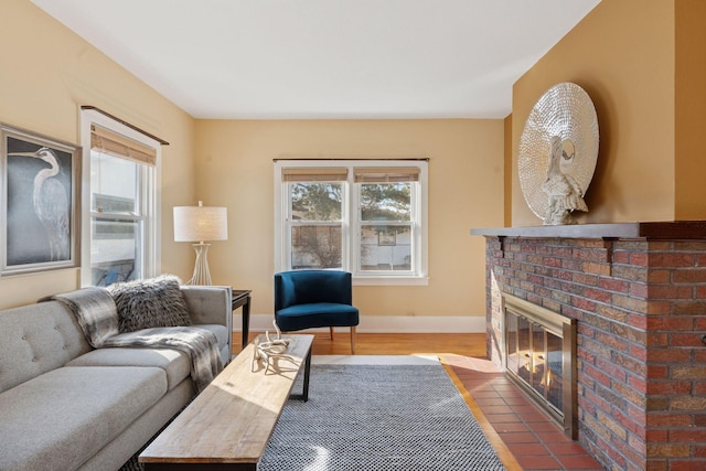 living area featuring a fireplace, baseboards, and wood finished floors