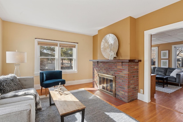 living area featuring a brick fireplace, wood finished floors, and baseboards