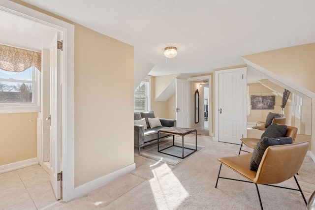 living area with a healthy amount of sunlight, light carpet, baseboards, and light tile patterned floors