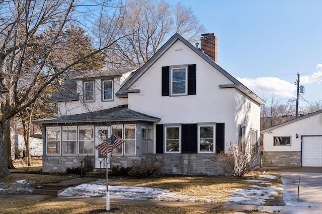 view of front of home featuring stone siding, a chimney, an outdoor structure, and stucco siding