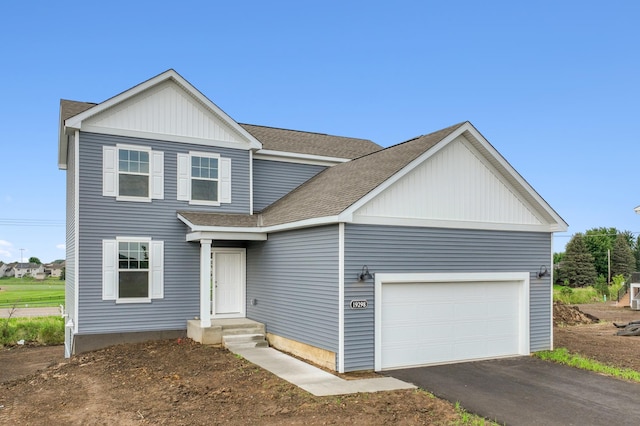 traditional-style house featuring a shingled roof, an attached garage, and aphalt driveway