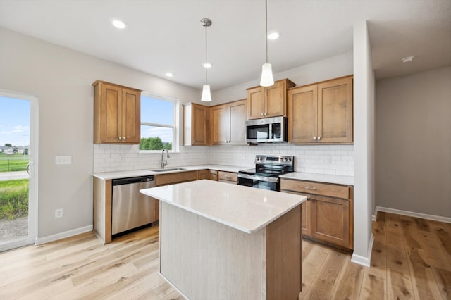 kitchen with light wood-type flooring, appliances with stainless steel finishes, backsplash, and a sink