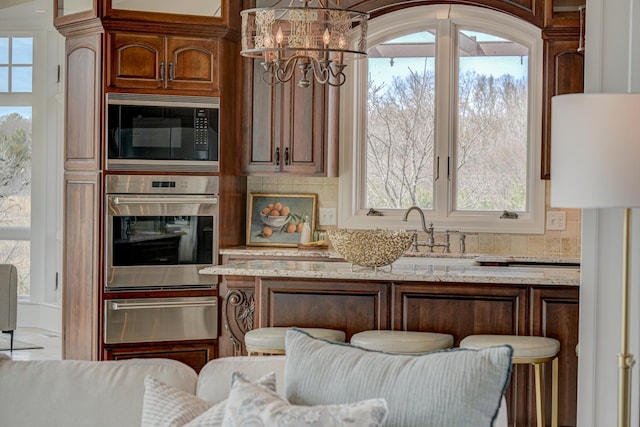 795 140th Ave, New Richmond, WI 54017 - kitchen featuring stainless steel appliances, a warming drawer, a chandelier, a breakfast bar area, and light stone countertops
