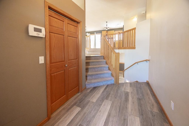 staircase with a chandelier, baseboards, and wood finished floors