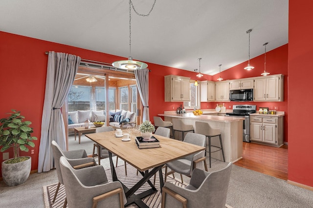 dining area with baseboards, high vaulted ceiling, and light colored carpet