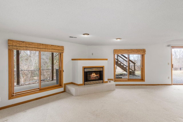 unfurnished living room with carpet flooring, baseboards, visible vents, and a fireplace