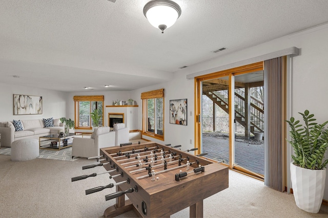 recreation room featuring carpet floors, a textured ceiling, and visible vents
