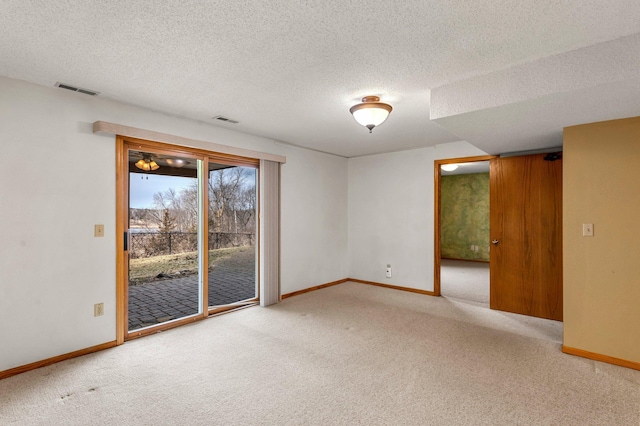 carpeted spare room with baseboards, a textured ceiling, and visible vents