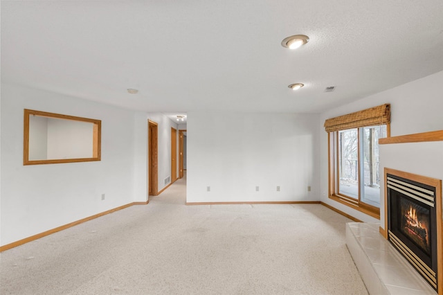 unfurnished living room featuring light colored carpet, baseboards, a glass covered fireplace, and visible vents
