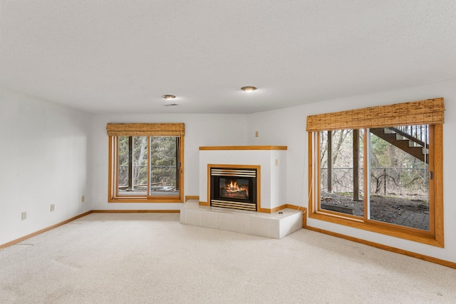 unfurnished living room with plenty of natural light, carpet, and baseboards