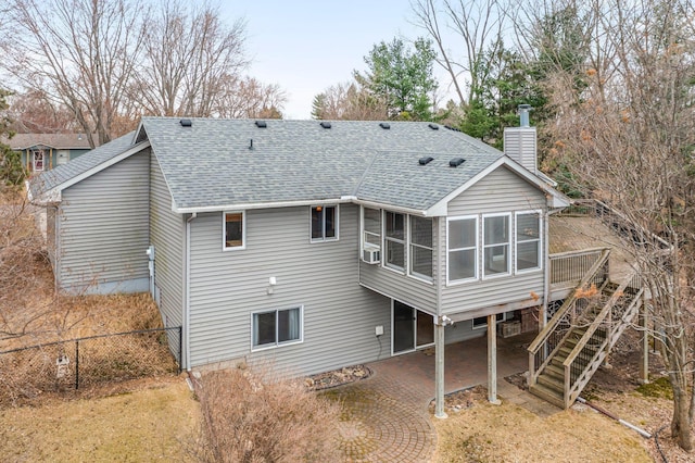 rear view of house featuring roof with shingles, a patio, a chimney, and a sunroom