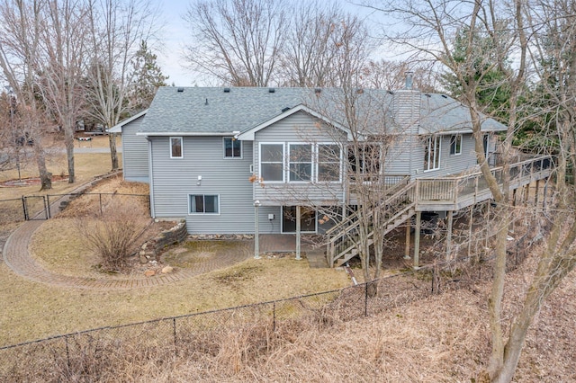 rear view of property with a deck, a fenced backyard, a chimney, a shingled roof, and stairway