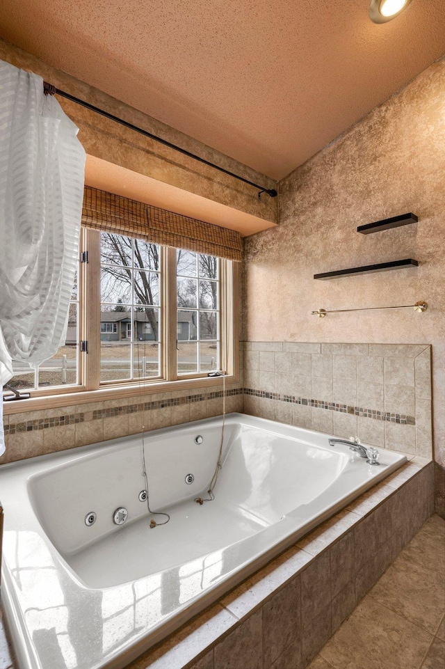 bathroom with tile patterned floors, a tub with jets, and a textured ceiling