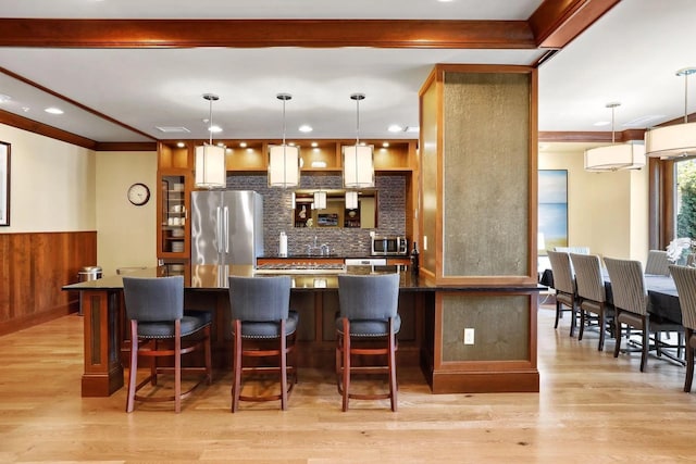 kitchen featuring tasteful backsplash, dark countertops, light wood-style flooring, appliances with stainless steel finishes, and a breakfast bar