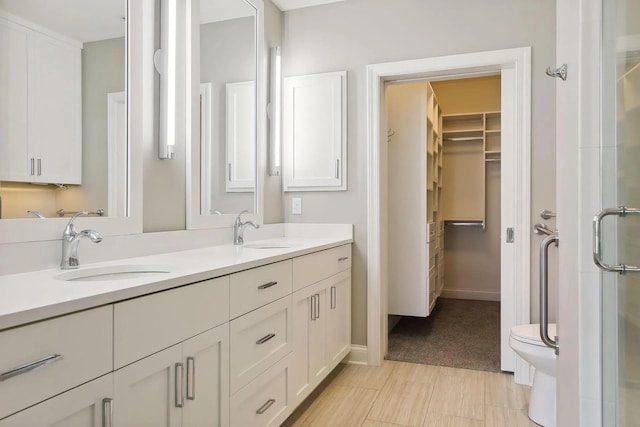 full bath with a stall shower, a sink, a spacious closet, and double vanity