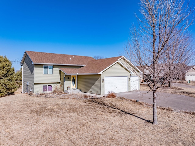 split level home with a shingled roof, driveway, and an attached garage