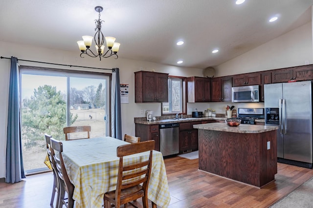 kitchen featuring appliances with stainless steel finishes, light wood-style flooring, dark brown cabinetry, and a center island