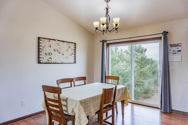 dining room featuring an inviting chandelier, baseboards, vaulted ceiling, and wood finished floors