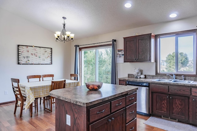 kitchen featuring light wood finished floors, visible vents, dark countertops, a sink, and stainless steel dishwasher