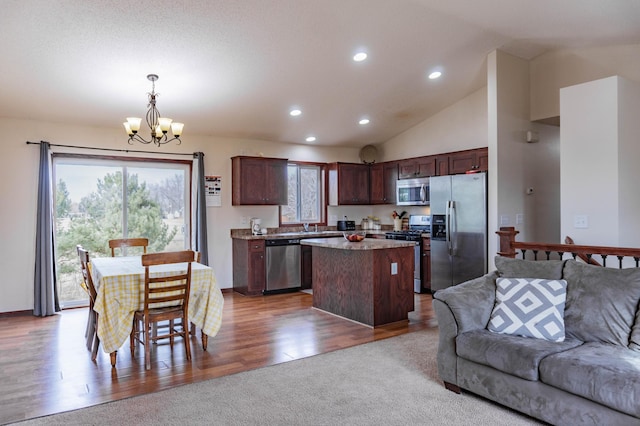 kitchen featuring appliances with stainless steel finishes, open floor plan, a center island, hanging light fixtures, and an inviting chandelier