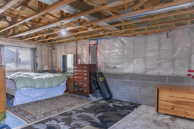 bedroom featuring electric panel and concrete block wall