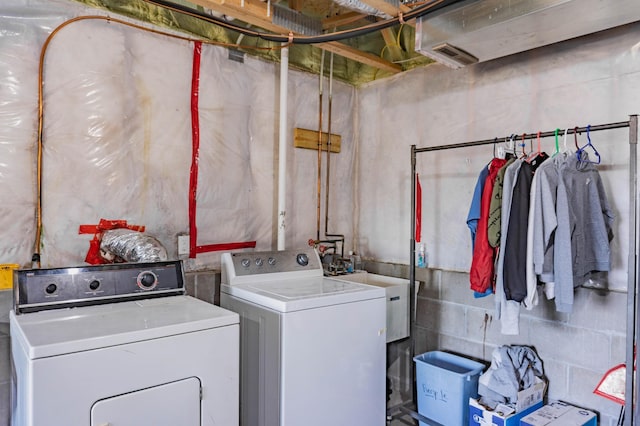 clothes washing area with laundry area, separate washer and dryer, and concrete block wall