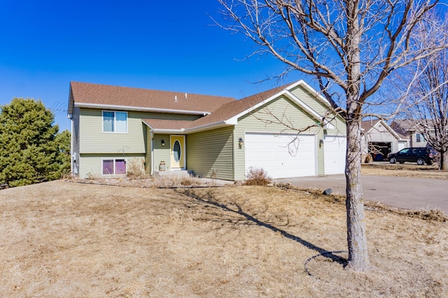 tri-level home featuring driveway, a garage, and roof with shingles