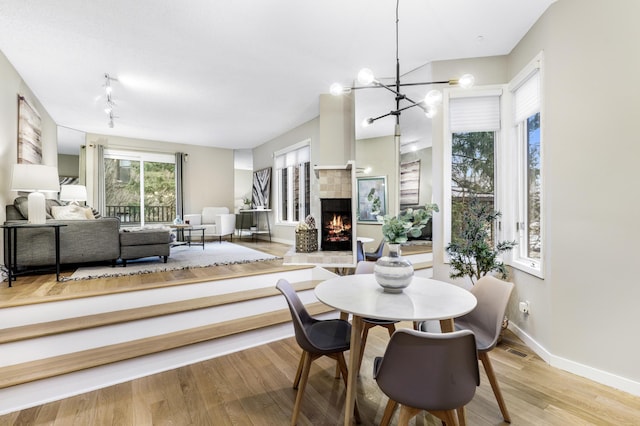 dining area featuring light wood-style floors, baseboards, visible vents, and a tiled fireplace