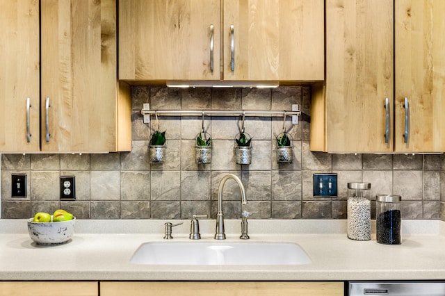 kitchen with tasteful backsplash, a sink, light countertops, light brown cabinetry, and stainless steel dishwasher