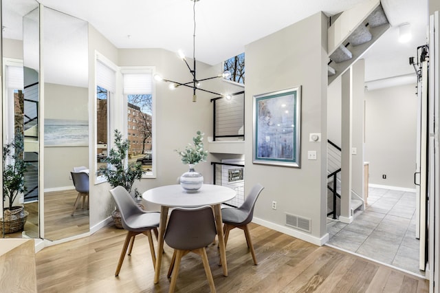 dining room featuring a notable chandelier, baseboards, visible vents, and light wood-style floors