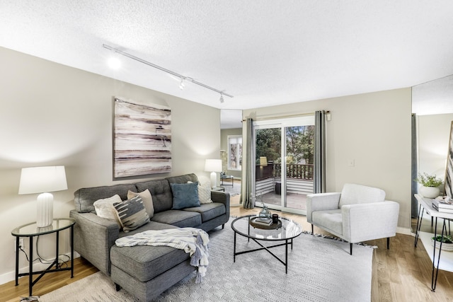 living area with light wood-style flooring, baseboards, and a textured ceiling