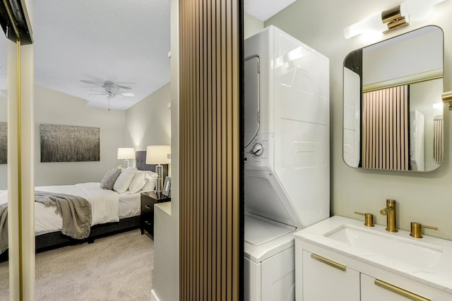 bedroom featuring light carpet, stacked washing maching and dryer, ceiling fan, and a sink